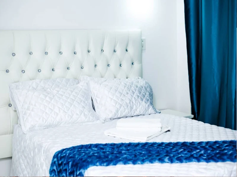 Guest bedroom with white tufted headboard and blue accents